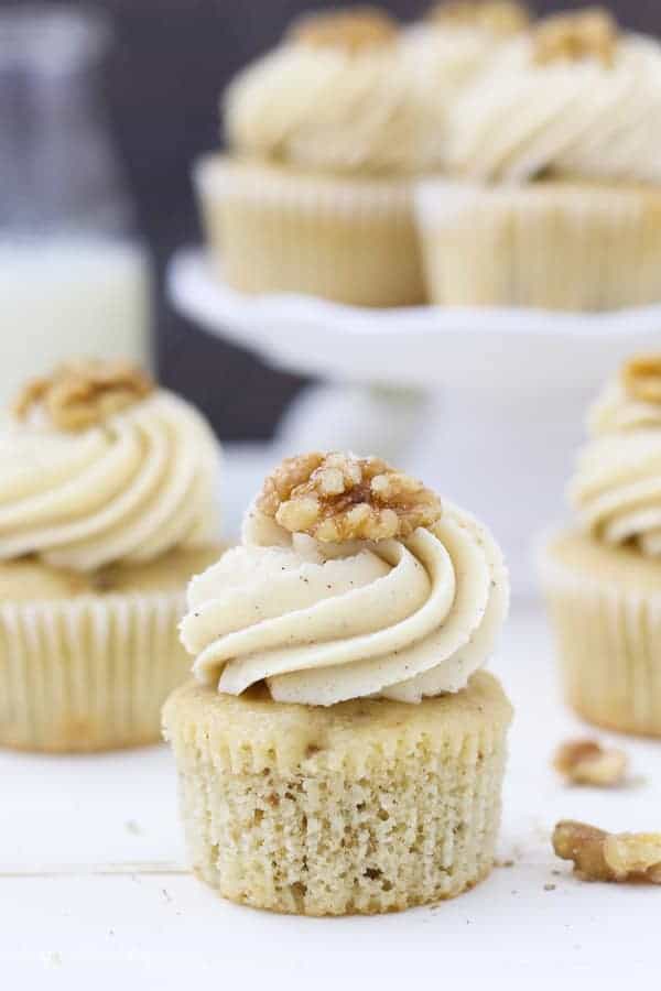 An unwrapped cupcake with a big swirl of frosting on top and a walnut on top