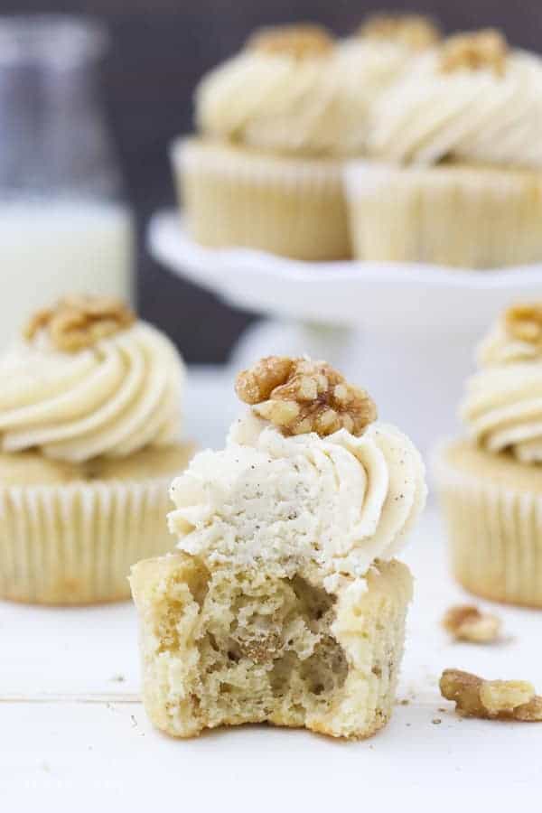 a big bite is taken out of this cupcake exposing the airy inside of the cupcake with walnuts.