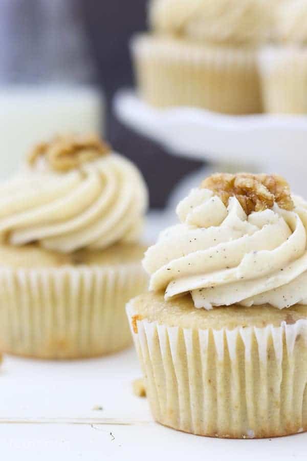 A close up shot of a cupcake with a big swirl of frosting and a walnut on top.