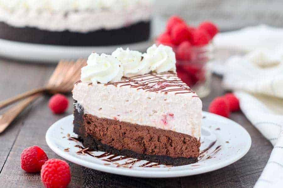 A wide screen shot of a big slice of chocolate mousse take with raspberries and whipped cream on top