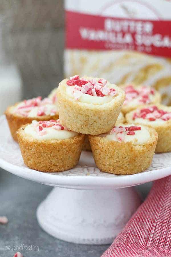 A small white cake stand filled with peppermint cookie cups and a red napkin