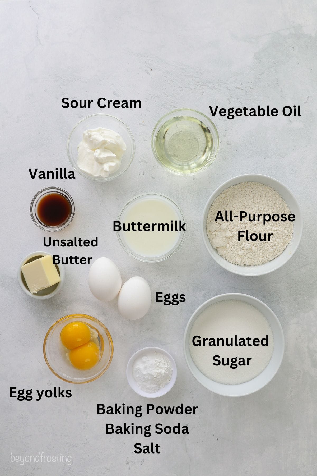 Ingredients for homemade yellow cupcakes with text labels overlaying each ingredient.