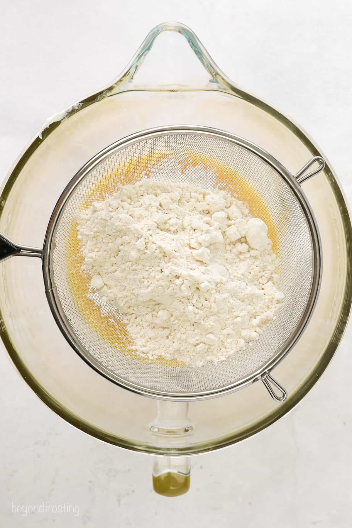 Dry ingredients added to wet cupcake batter in a glass bowl.