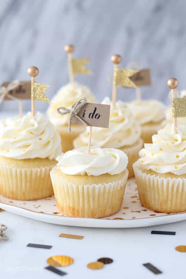 These engagement themed cupcakes are super cute decorated with a buttercream rose and a little gold flag cupcake topper