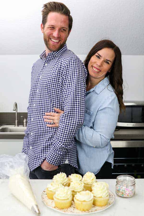 These cute husband and wife engagement photos in their home kitchen featuring some engagement themed cupcakes