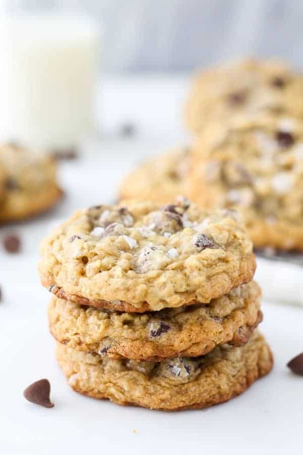 A stack of 3 chocolate chip oatmeal cookies, the cookie on top has large flakes of sea salt on top