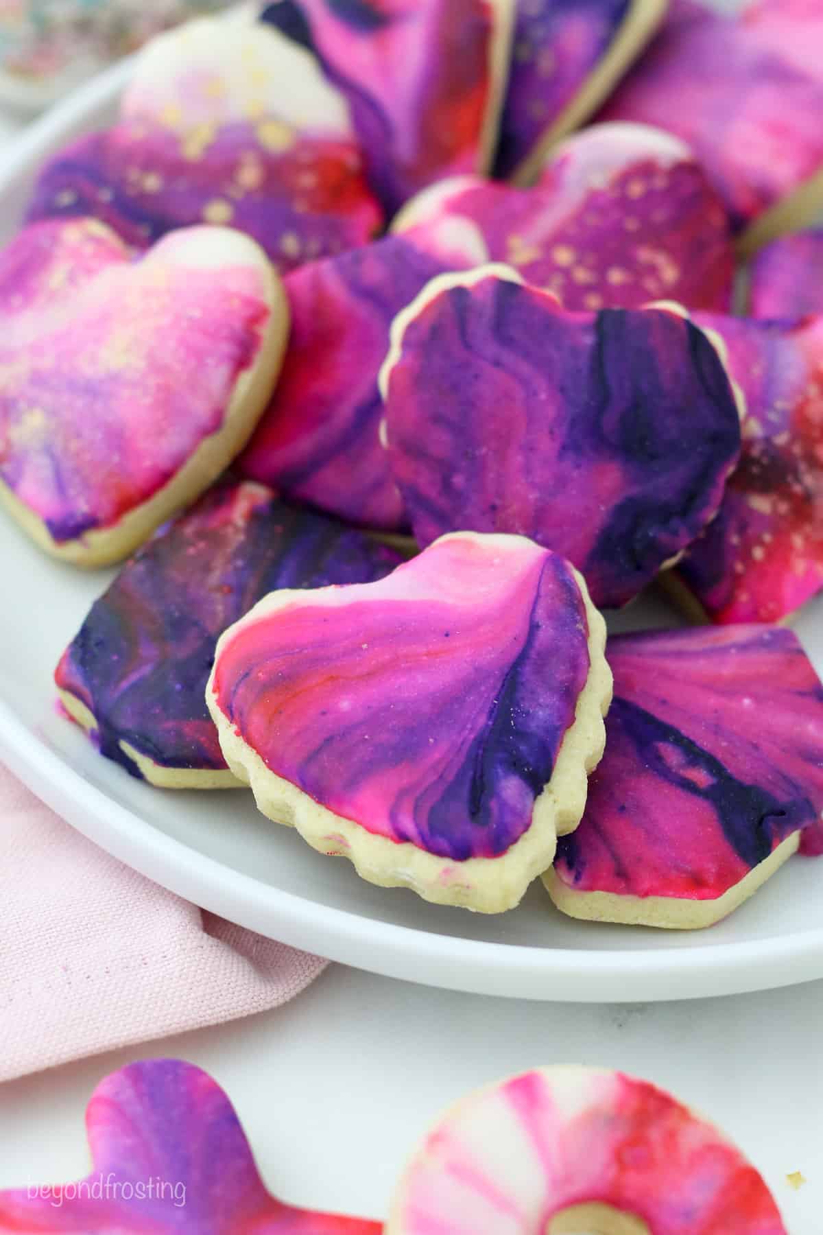 Heart-shaped Valentine's Day sugar cookies decorated with marbled icing on a plate.