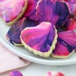 A gorgeous plate of mini sugar cookie decorated with marble icing for Valentine's day featuring red, pink, purple and white.