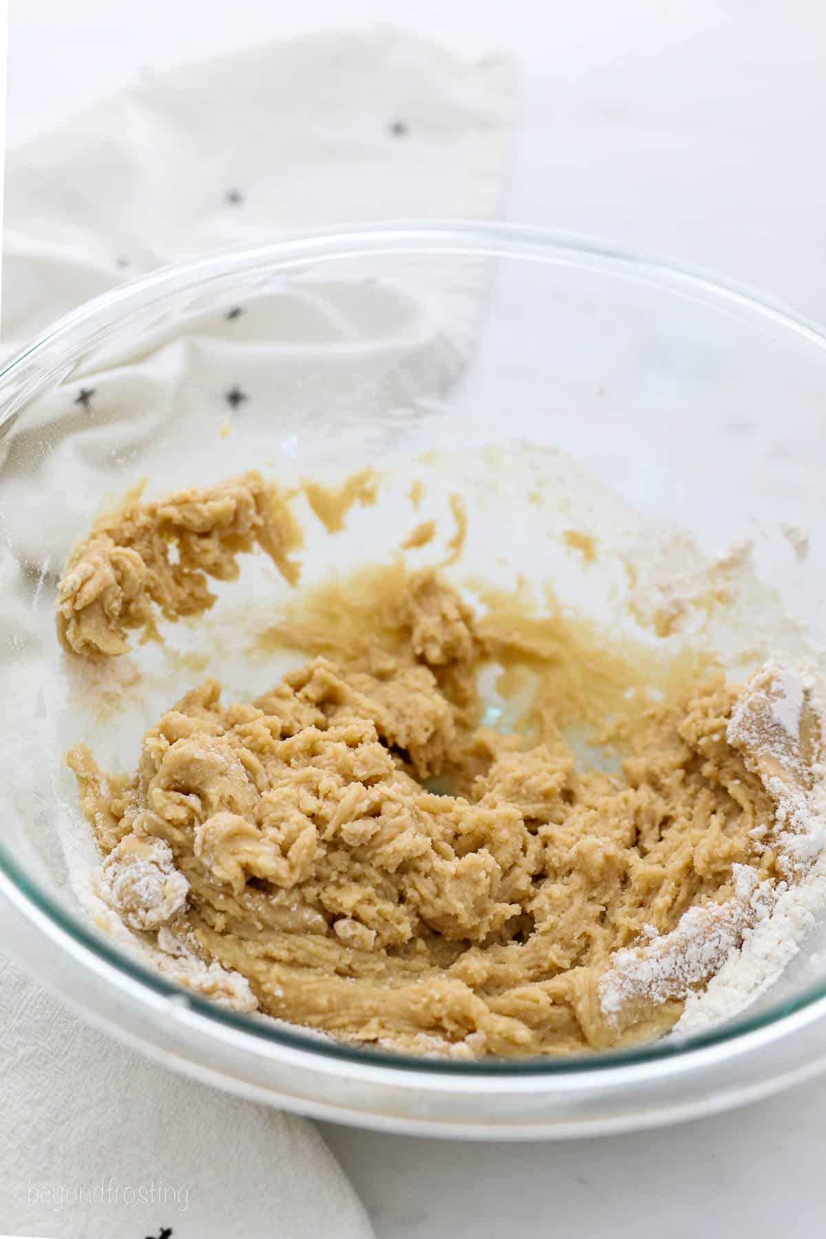 Beaten cookie dough in a glass mixing bowl.
