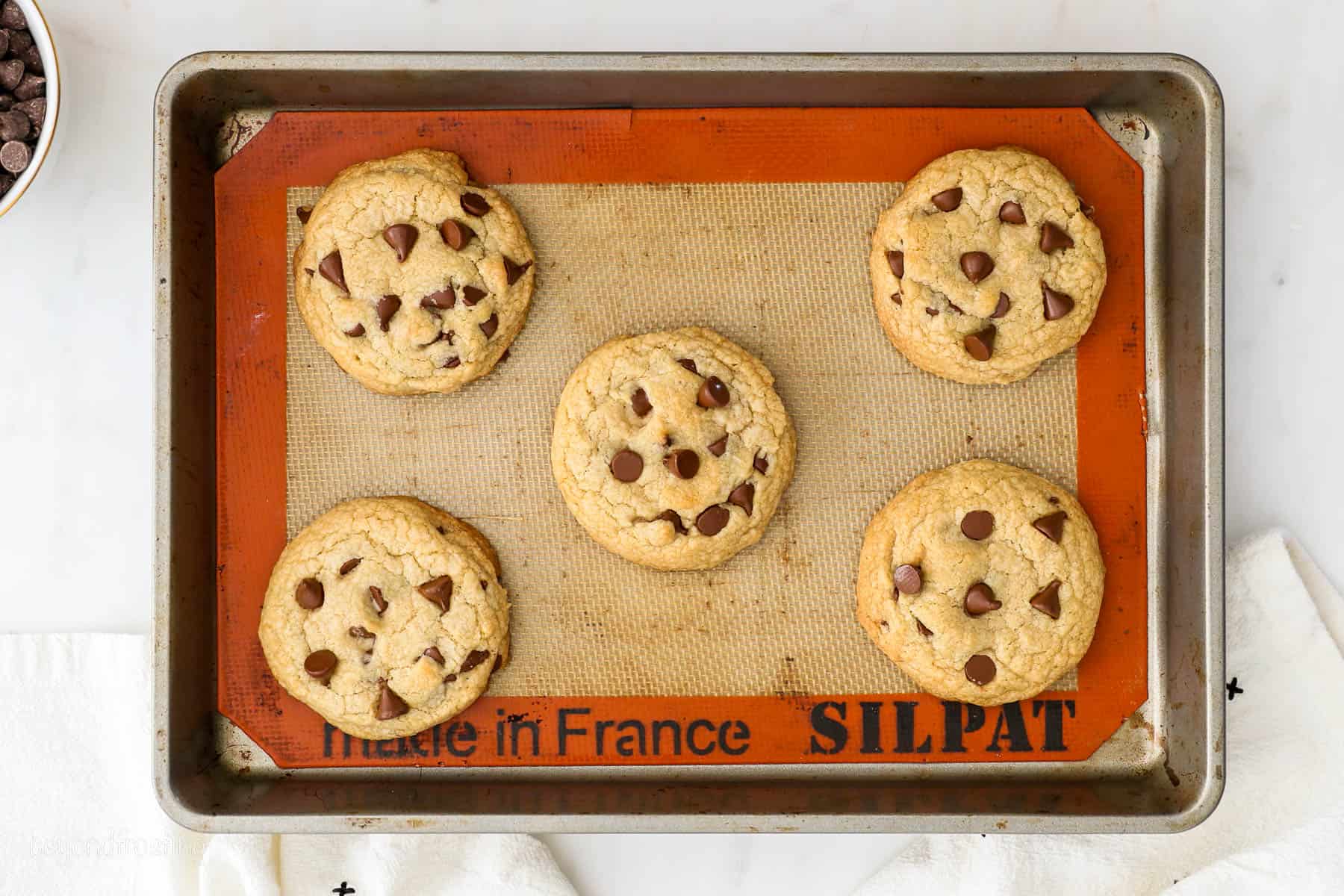 Overhead view of freshly baked chewy chocolate chip cookies on a Silpat lined baking sheet.