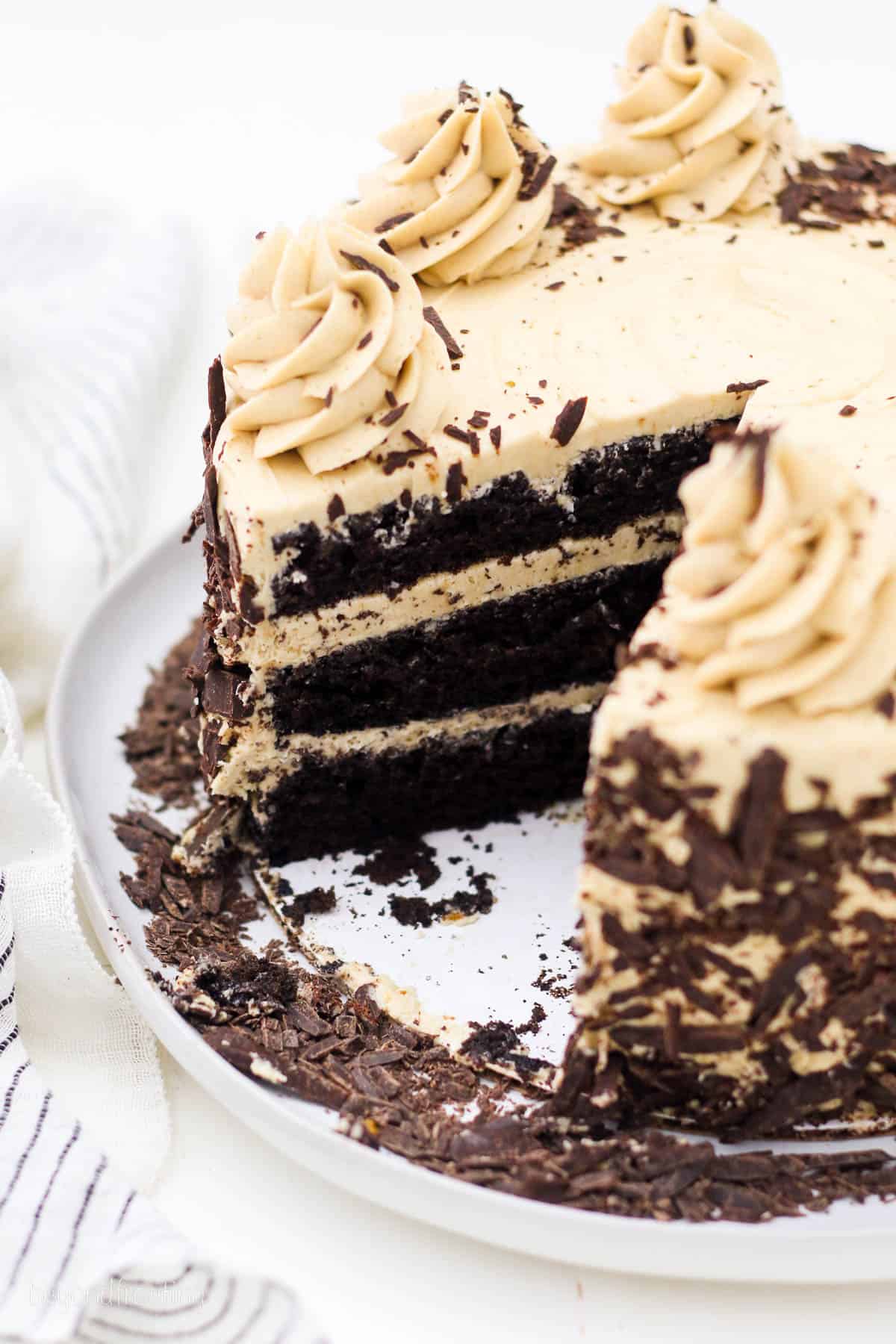 A frosted and decorated chocolate mocha cake with a slice missing.