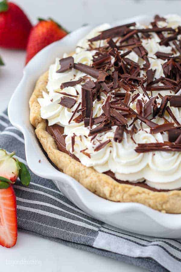 An overhead shot of half of a chocolate pie showing the whipped cream topping and chocolate shavings.