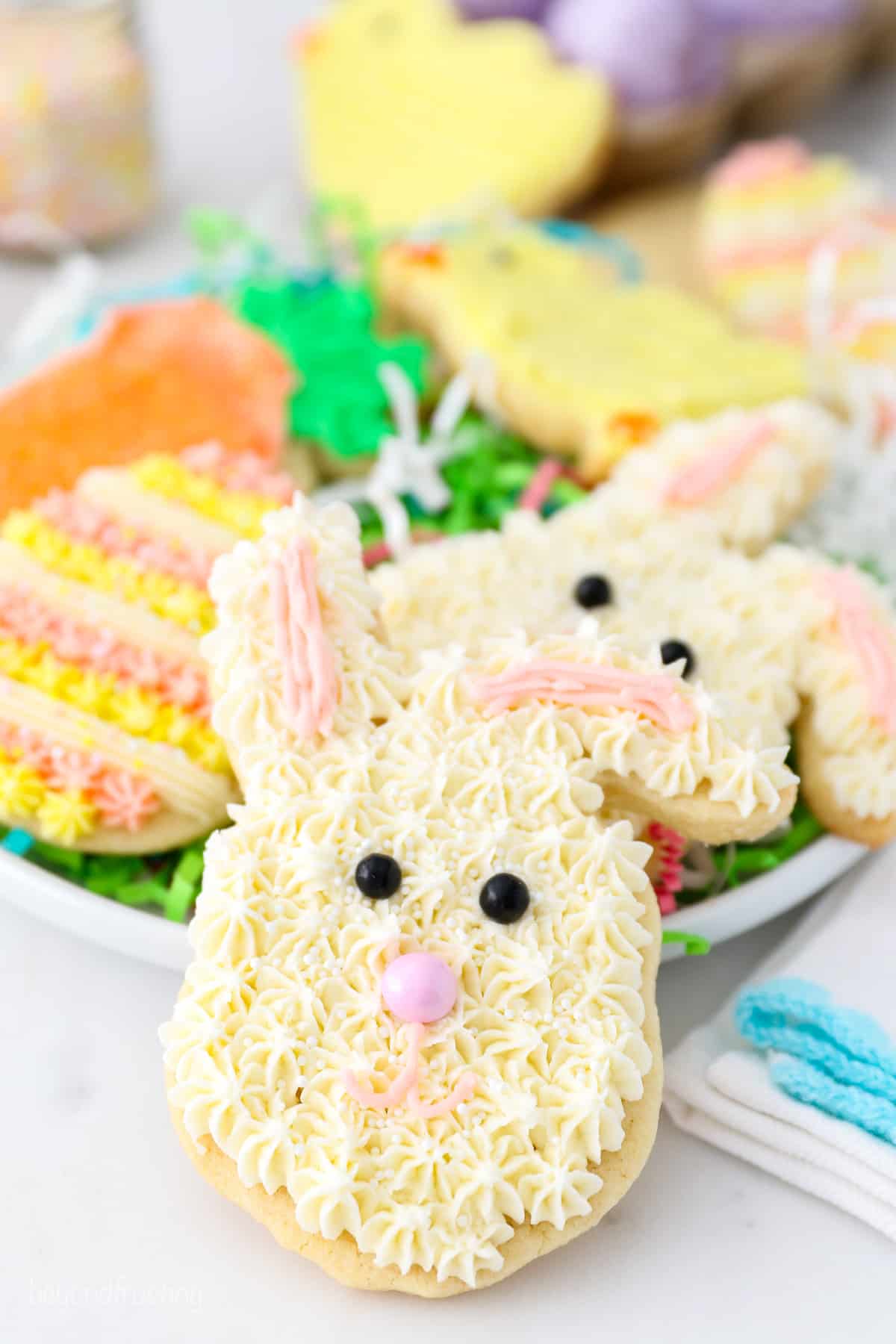 An Easter bunny cookie propped up against a plate of frosted Easter sugar cookies.