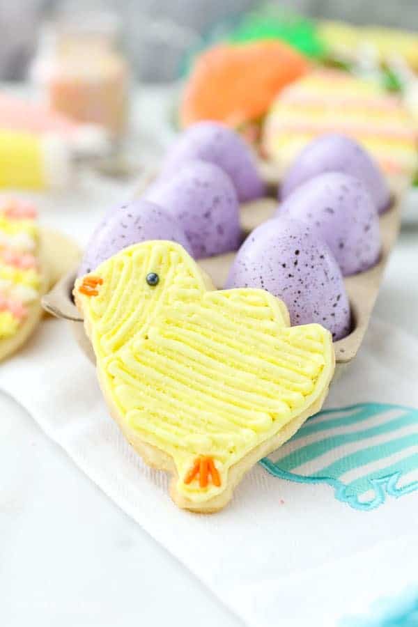 A baby chick sugar cookie decorated with yellow buttercream.