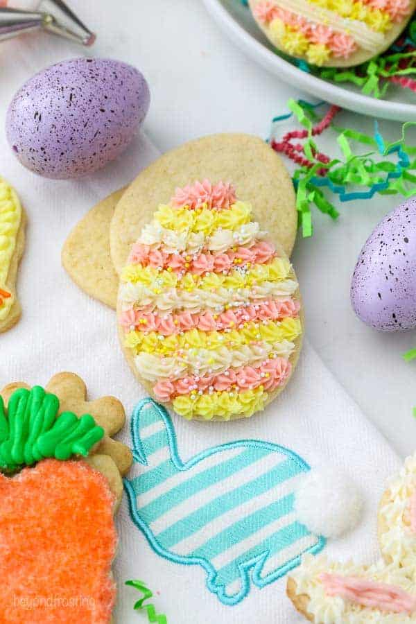 Easter egg sugar cookie with pink, yellow and white buttercream and sprinkles.