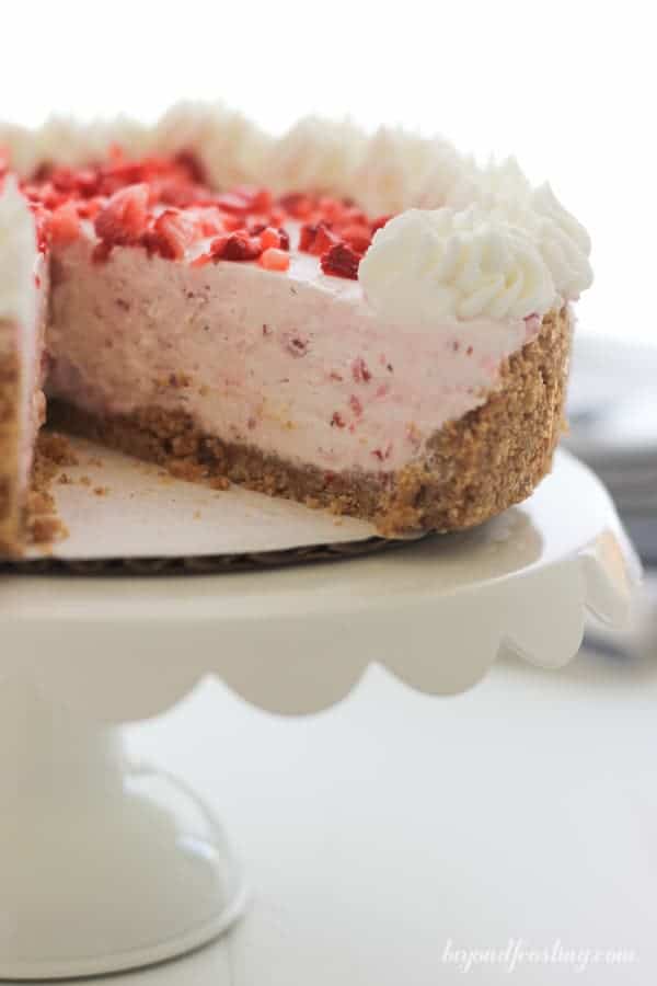 A no-bake Strawberry pie is sitting on a white ruffled cake plate.