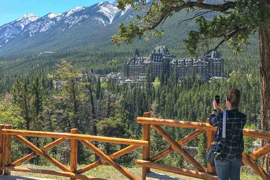 Surprise Corner in Banff National Park overlooking the Fairmont Hotel, women is taking a picture with her iphone