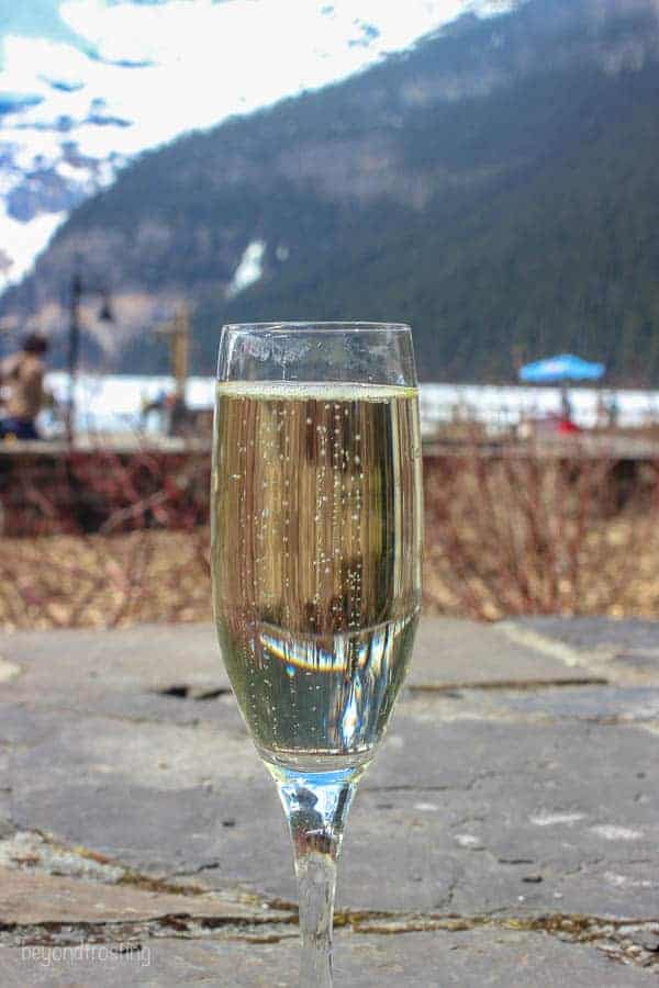 A glass of champagne with Lake Louise hiding in the background