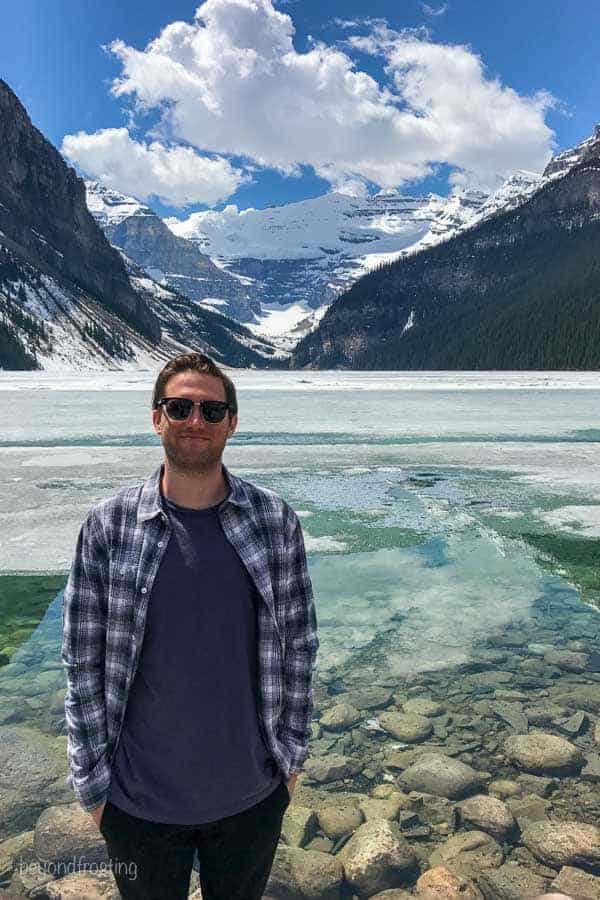 Gorgeous view of Lake Louise partially covered in ice with crystal clear water.