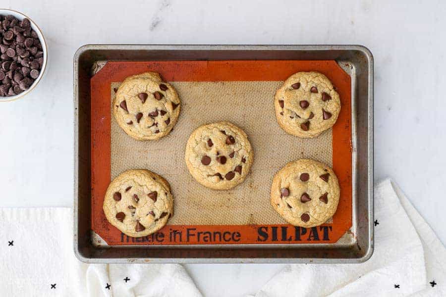 An overhead shot of a baking sheet with baked chocolate chip cookies on it