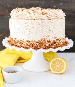 A Lemon Coconut Cake on a Cake Stand Next to Half a Lemon