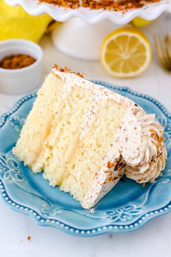 An overhead shot of a layered lemon cake sitting on a teal plate.