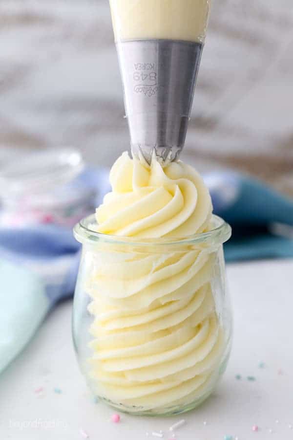 A large piping bag with Ateco 849 piping tip is piping a big swirl of frosting in a jar