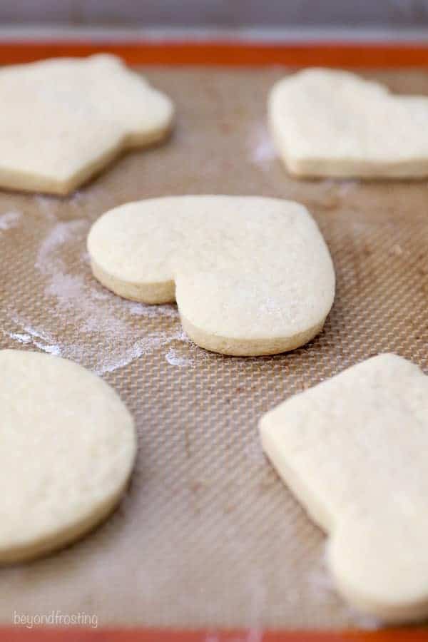 A close up of a baked, heart-shaped sugar cookie sitting on a silpat liner