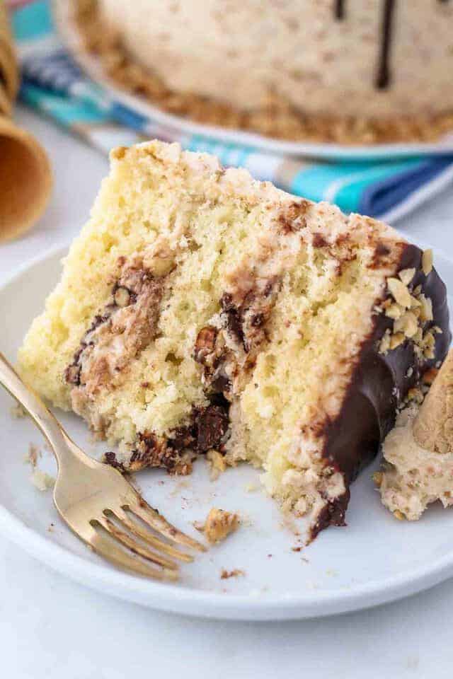 A sliced of layered drumstick cake with a few bites missing. There's lots of cake, chocolate and peanuts