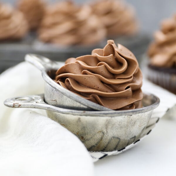 A vintage measuring cup filled with silky chocolate Swiss Meringue Buttercream