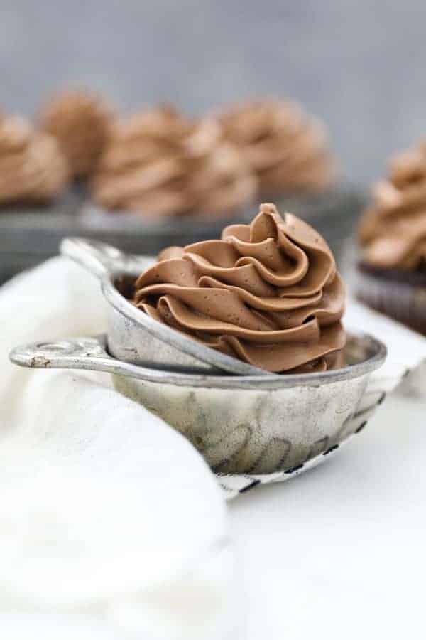 A vintage measuring cup filled with silky chocolate Swiss Meringue Buttercream
