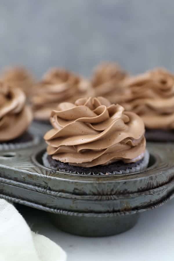 A vintage cupcake pan with chocolate cupcakes frosted with a silky chocolate buttercream