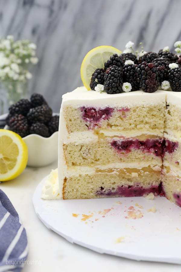 A layered lemon blackberry cake with a couple slices missing showing the inside of the cake