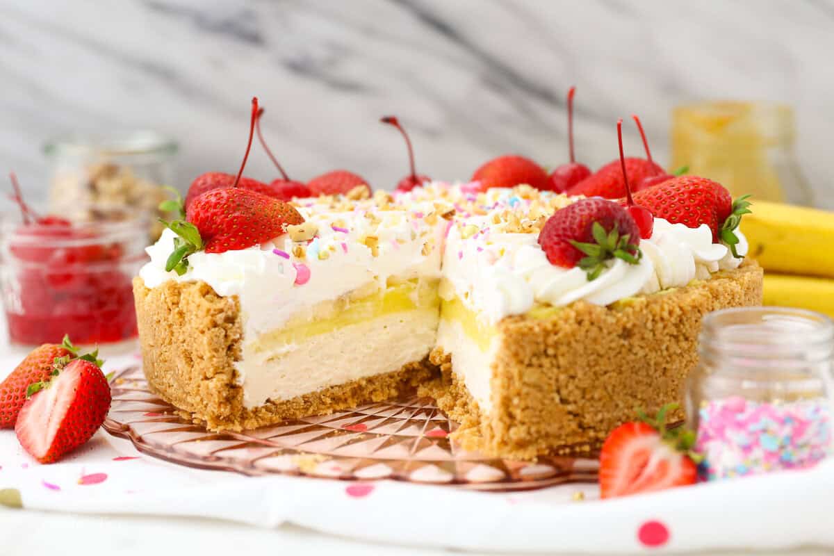 Banana split pie has all the flavors you love in a banana split, with creamy no-bake cheesecake, banana pudding, and all the sundae toppings! No-bake banana split pie topped with whipped cream, cherries, and sprinkles, with a large slice missing.
