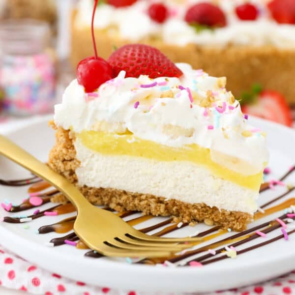 A slice of banana split pie topped with whipped cream, maraschino cherries, and sprinkles on a plate.