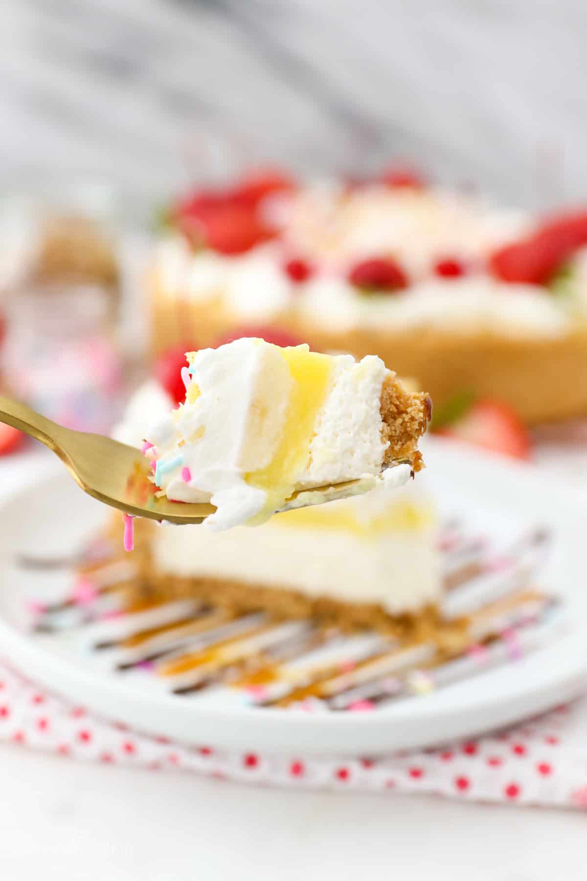 Banana split pie has all the flavors you love in a banana split, with creamy no-bake cheesecake, banana pudding, and all the sundae toppings! Close up of a forkful of banana split pie with a slice of pie on a plate in the background.