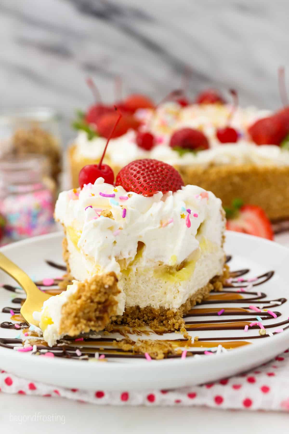 Banana split pie has all the flavors you love in a banana split, with creamy no-bake cheesecake, banana pudding, and all the sundae toppings! A forkful resting next to a slice of banana split pie topped with whipped cream and traditional sundae toppings.