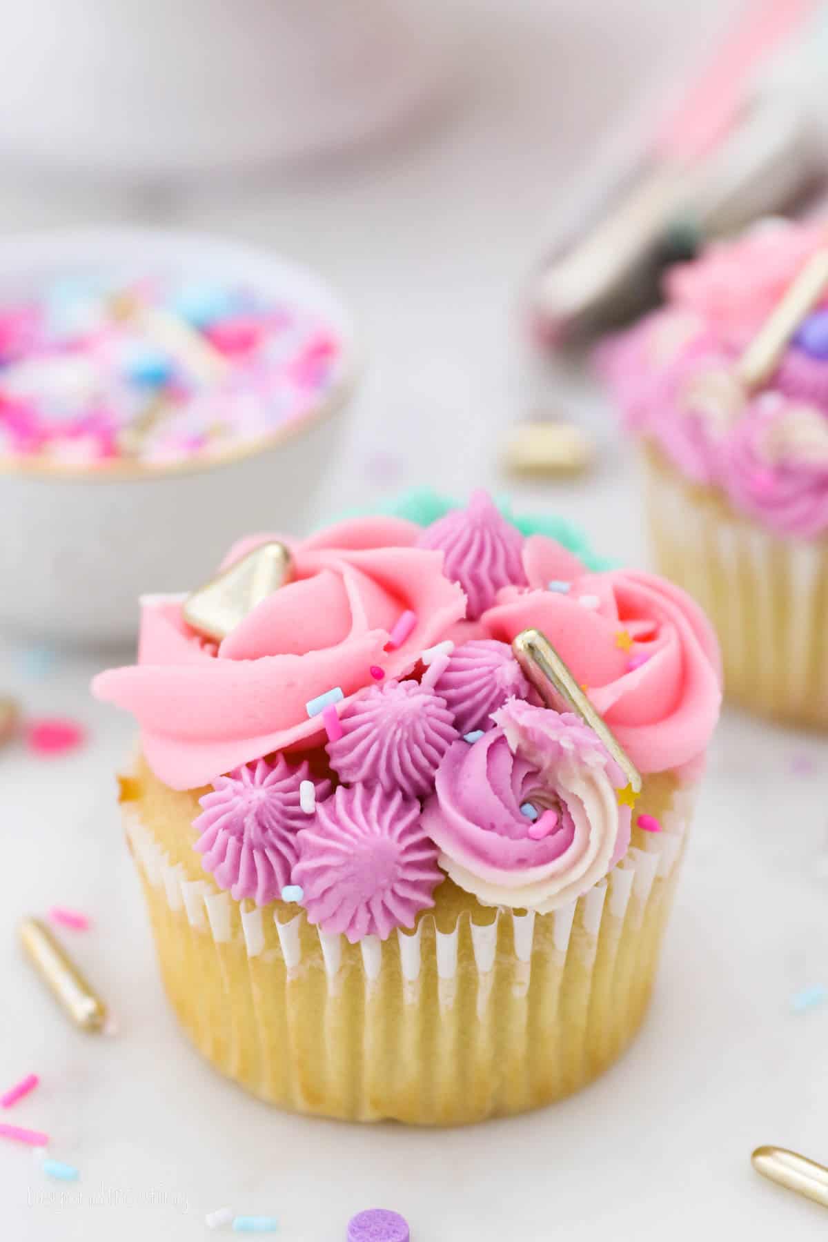 Close up of a unicorn cupcake frosted with brightly colored buttercream swirls.