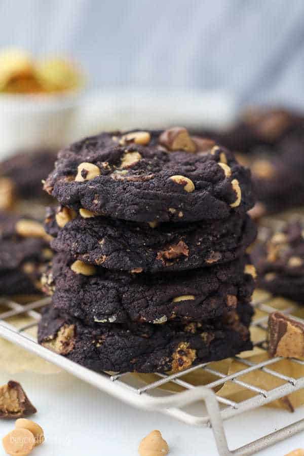A stack of 4 dark chocolate peanut butter cookies sitting on a wire rack.