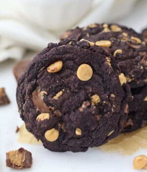 A perfectly shaped chocolate peanut butter cookie with a melted peanut butter cup and peanut butter chips on top.