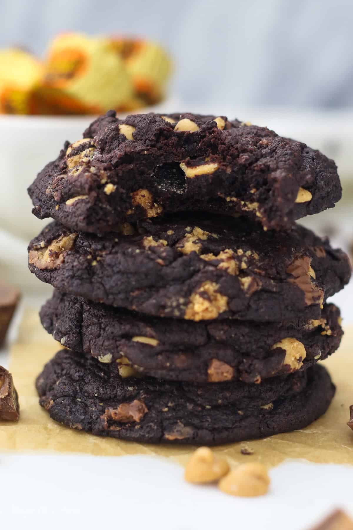 A stack of chocolate peanut butter cookies on a countertop with a bite missing from the top cookie.