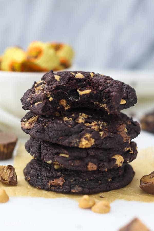 A stack of 4 chocolate peanut butter cookies, the cookie on top has a big bite taken out of it