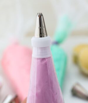 A piping bag fitted with a coupler and filled with purple frosting