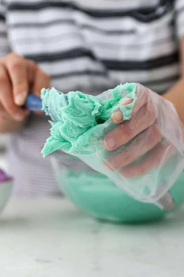 A piping bag folded over a hand, while the other hand is using a spatula to fill the bag