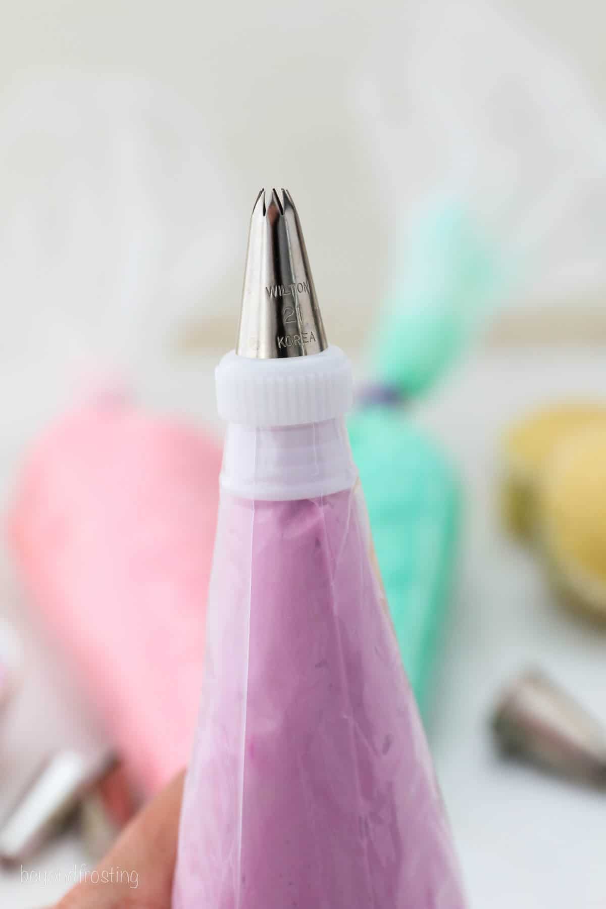 Close up of a piping bag filled with purple frosting, fitted with a piping tip and coupler set.