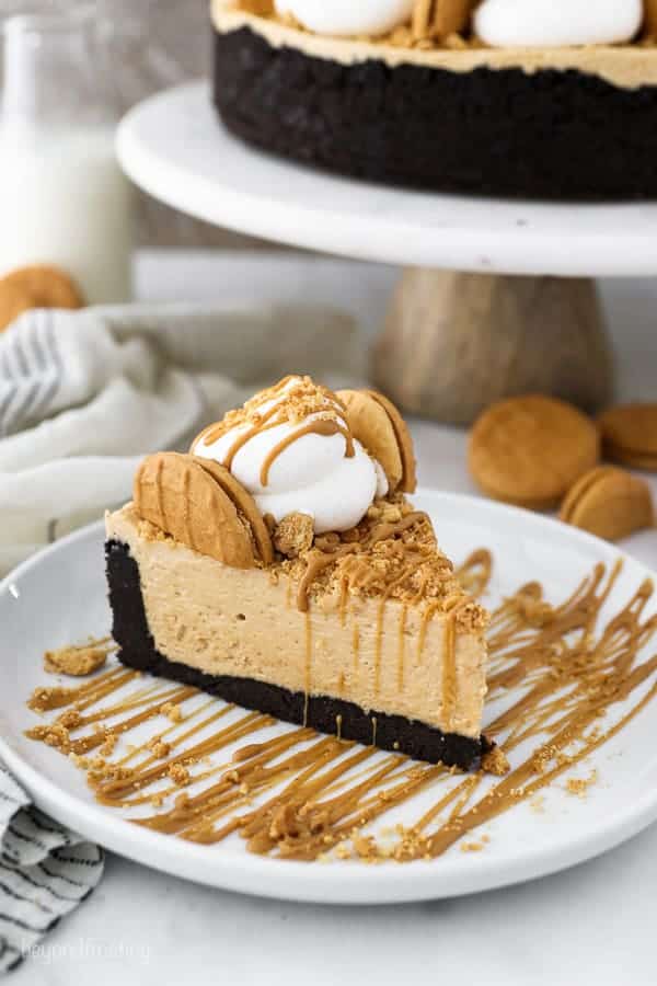 A slice of peanut butter pie is topped with whipped cream and Nutter Butter cookies, it's drizzled with more peanut butter. It looks divine.
