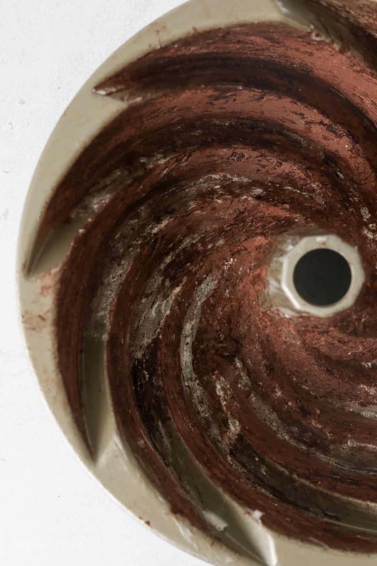 Overhead view of a greased bundt pan coated with cocoa powder.