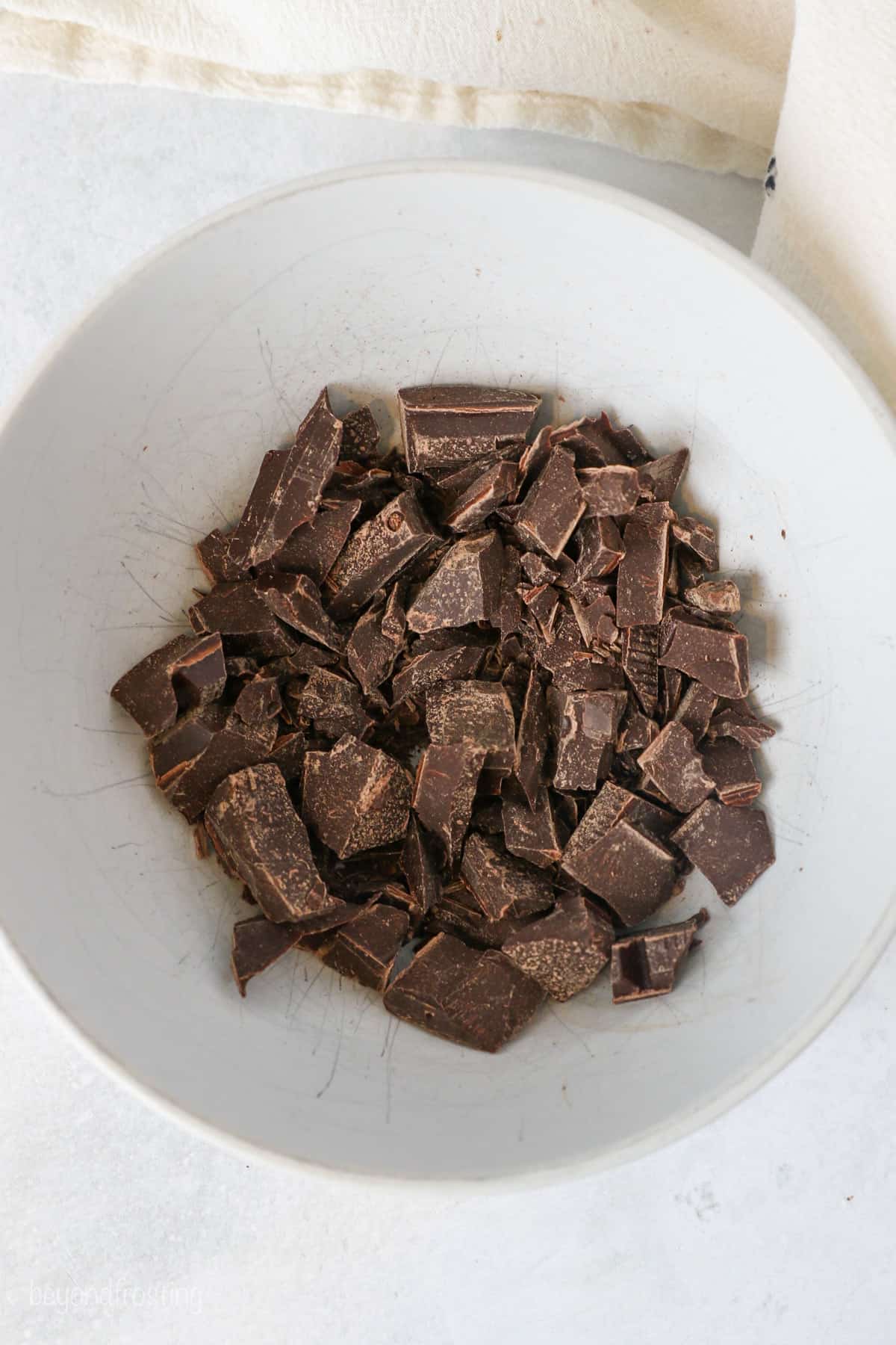 Chopped chocolate in a white bowl.