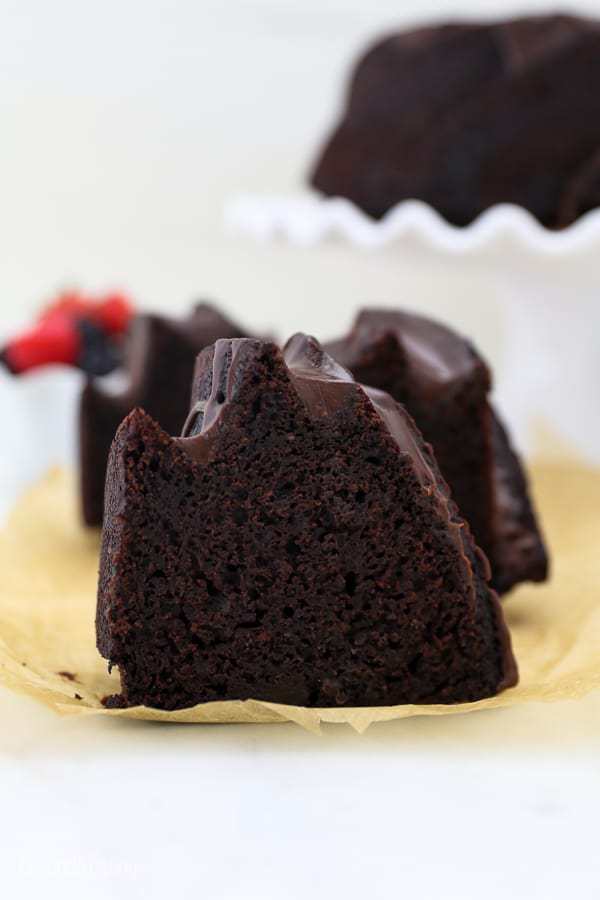 A slice of chocolate bundt cake on a crumbled piece of brown parchment paper.