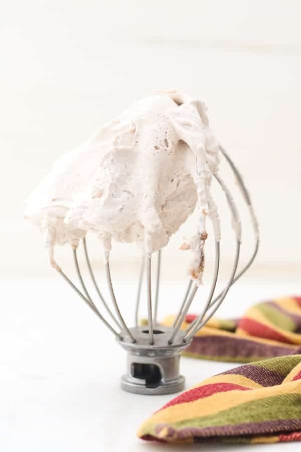 A pretty mixing bowl whisk with swirls of whipped cream and a beautiful fall napkin draped next to it